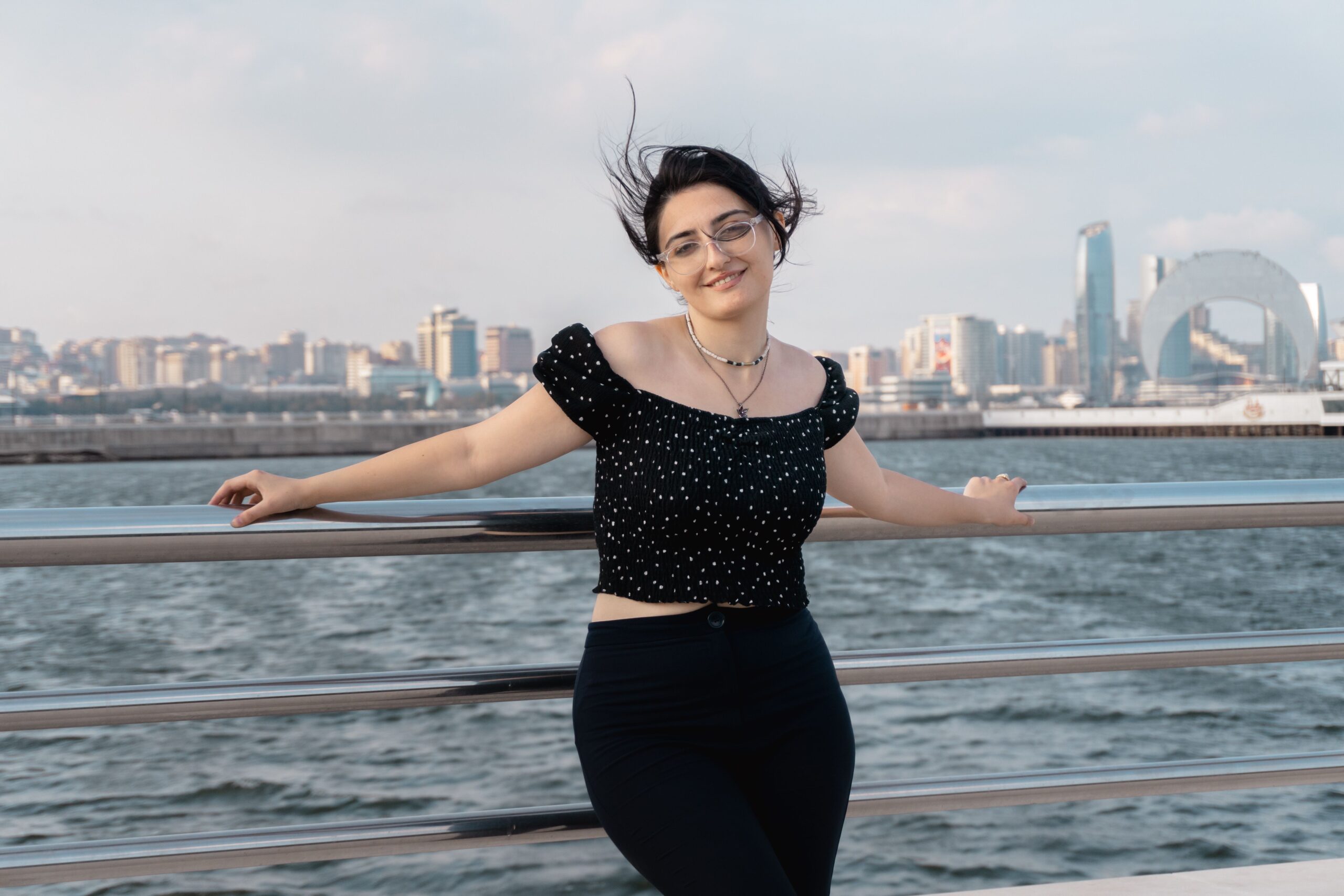 A woman enjoying a bright day by the Baku waterfront with the city skyline in the background.