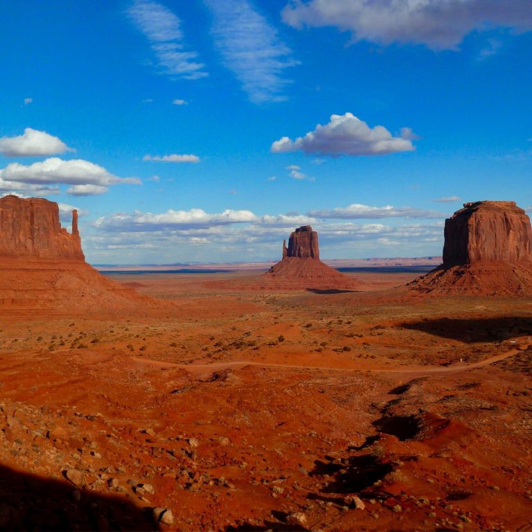 Scenic view of Monument Valley mesas framed by blue skies and clouds in Arizona, USA.